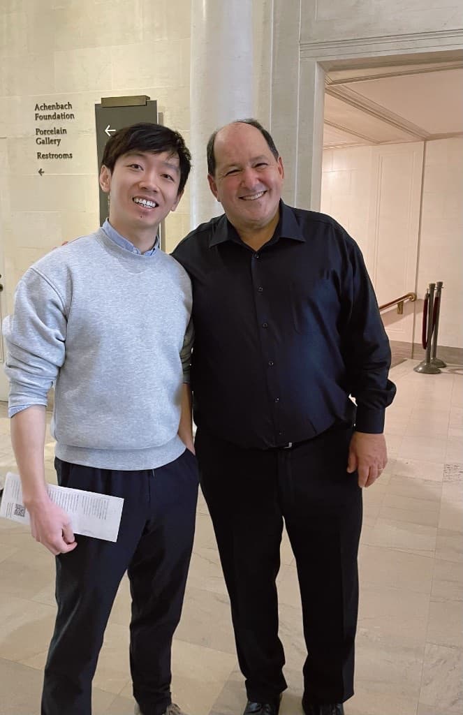 Eric Liu, the younger man on the left in a grey sweatshirt, with his piano teacher at Eric Liu Piano Studio